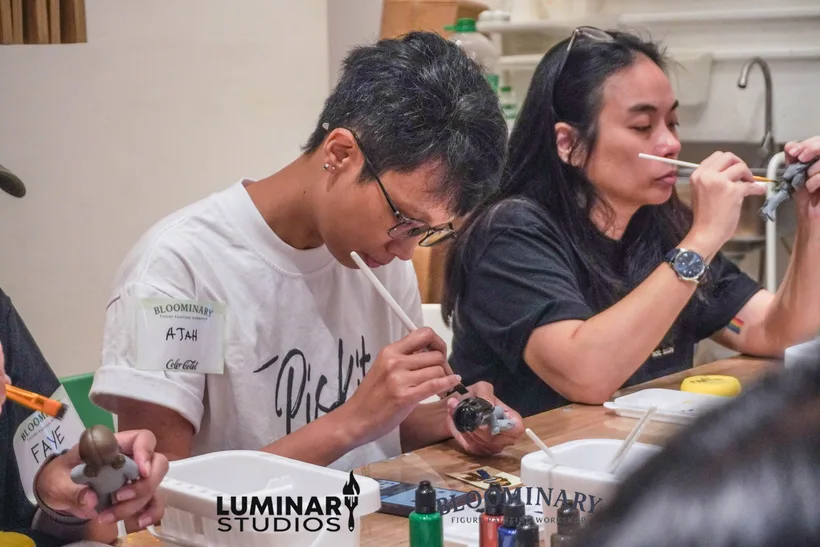 Painters focused on brushwork at the BINI figure workshop table