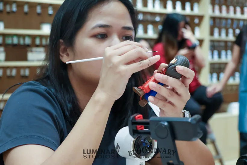 Close-up painting the face and eyes of a custom BINI 3D printed figurine