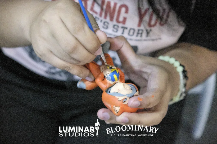 Hand painting a custom 3D resin BINI figure with orange accents