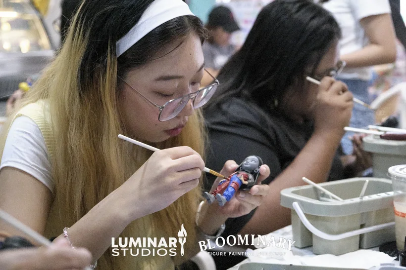 Painter detailing fine brushwork on a custom BINI 3D resin figurine