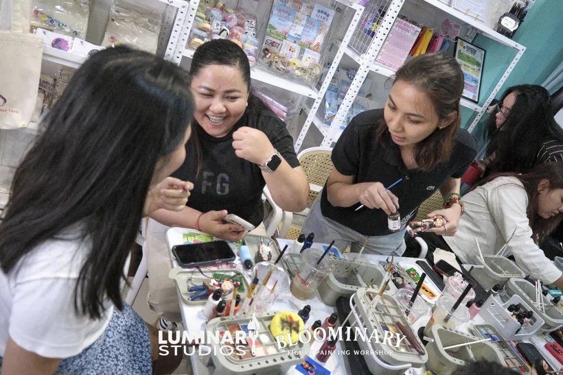 Friends laughing together at the BINI figure painting table
