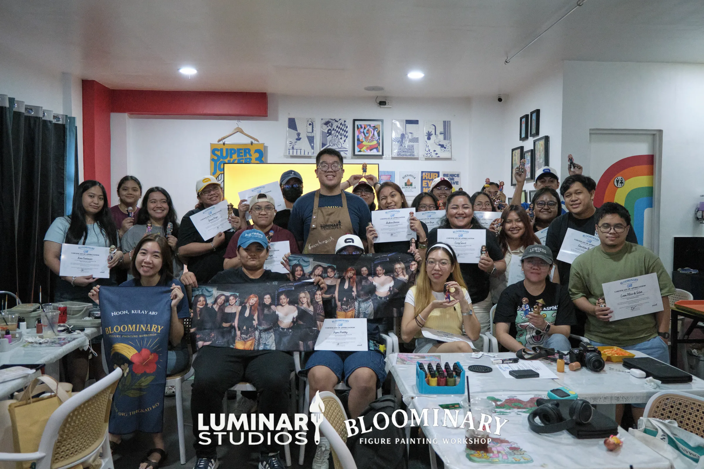 Bloominary workshop attendees holding painted BINI OT8 custom figures and completion certificates